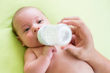 father feeding milk his baby infant from bottle