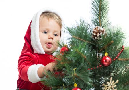 pretty Santa Claus baby decorating Christmas tree isolated on whiteの写真素材