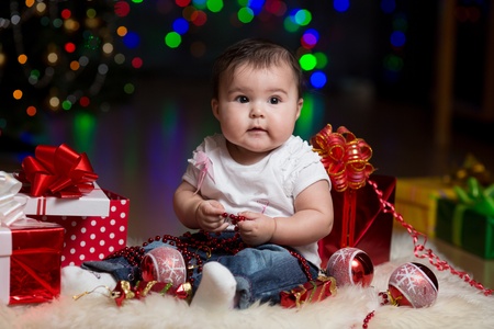 baby girl with gifts under Christmas treeの写真素材