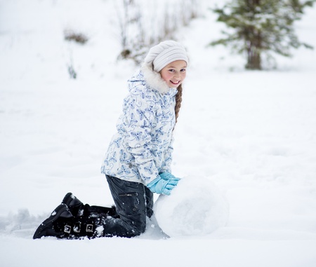 kid making snowman in winter parkの写真素材