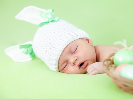 adorable baby dressed in Easter bunny cap with eggsの写真素材