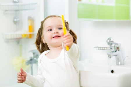 kid girl brushing teeth in bathroomの写真素材