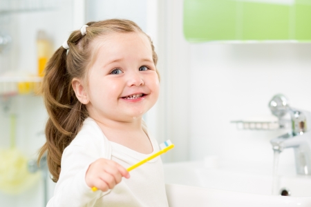 Smiling child girl brushing teeth in bathroomの写真素材