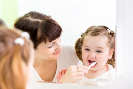 mother kid brushing kid teeth