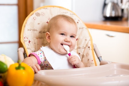 smiling baby eating food on kitchenの写真素材