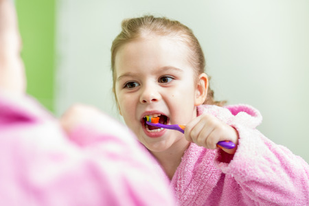 kid girl brushing teeth in bathroomの写真素材