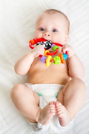 baby lying on back weared diaper with toyの写真素材