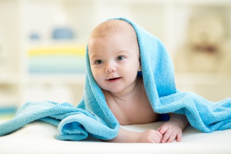 baby boy under blue towel after bath indoorsの写真素材