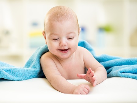 cute baby boy hidden in blue towel after bath