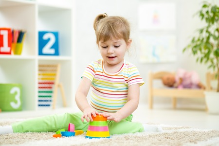 child girl playing with colorful construction set in nurseryの写真素材