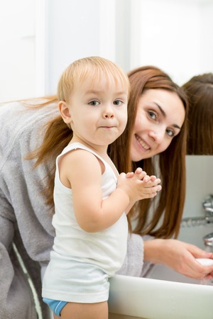 Happy mother and kid washing hands with soap together in bathroomの写真素材