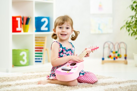kid girl playing guitar toy at homeの写真素材