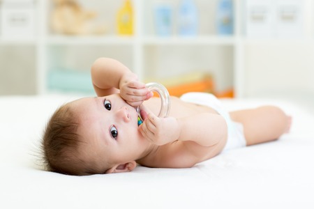 baby with teether toy weared diaper at homeの写真素材