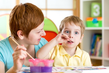 mom and kid boy painting together at homeの写真素材