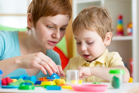 child boy and woman play colorful clay toy at nursery or kindergartenの写真素材