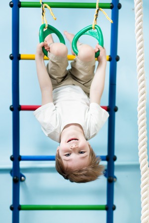 kid boy hanging on gymnastic rings at home