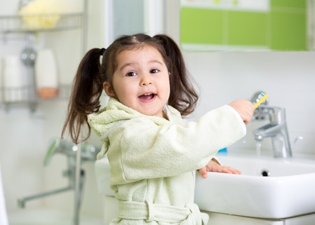 Smiling child girl brushing teeth in bathroomの写真素材