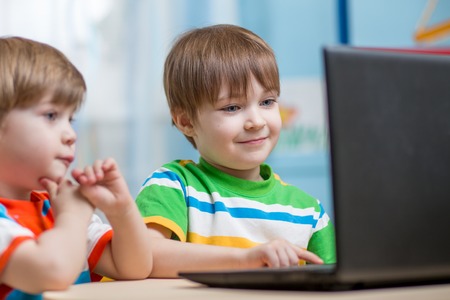 happy children boys looking at laptop indoors