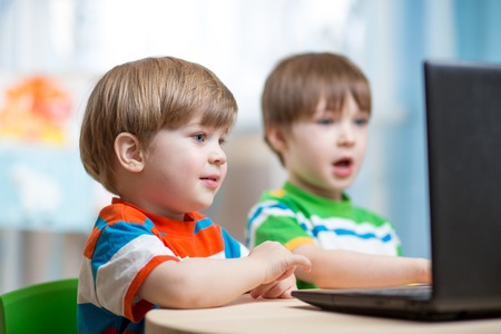 happy children boys working at laptop indoors