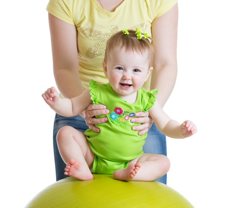 mother playing with baby girl on fitness ballの写真素材