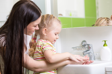 kid and mother washing hands with soap in bathroomの写真素材