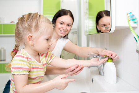 Happy kid with mom washing hands in the bathroomの写真素材