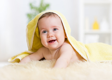 Adorable happy baby girl under towel indoorの写真素材