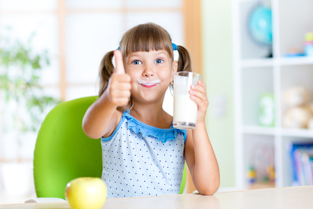 child girl drinks milk and showing thumb up