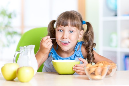 cute child girl eating cereal with milk in nursery cute child girl eating cereal with milk in nursery
