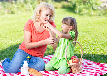 Happy family at summer vacation concept. Mother and daughter kid having picnic playing in park outdoors.の写真素材