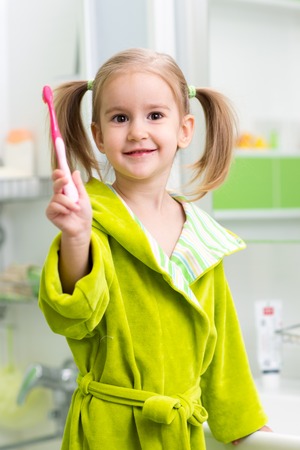 Smiling child kid girl brushing teeth in bathroomの写真素材
