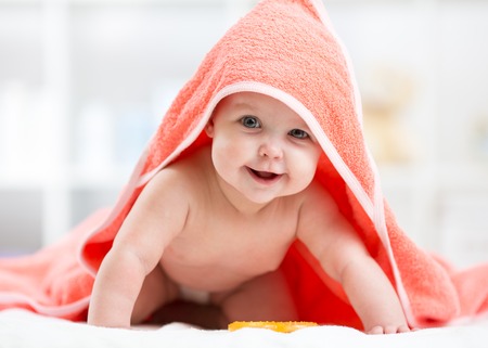 Adorable baby child under a hooded towel after bathingの写真素材