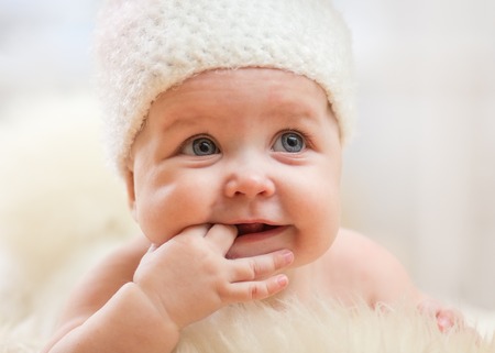 Portrait of adorable smiling baby girl lies on fur underlay