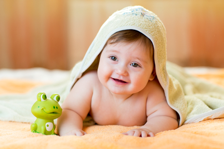Cheerful baby child under a hooded towel after bathingの写真素材