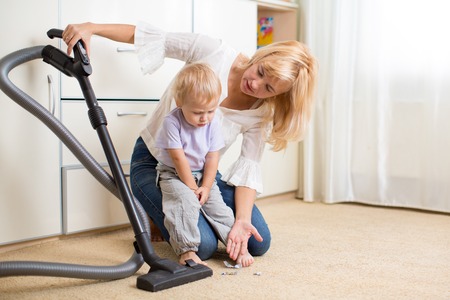 Mother teaches her child son room cleaning with vacuun cleanerの写真素材