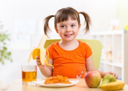 Beautiful child girl eating healthy food fruits at home Beautiful child girl eating healthy food fruits at home