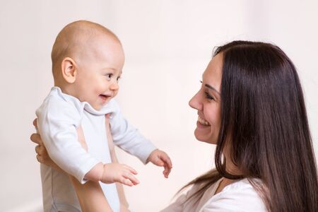Happy mother holding and looking at baby son