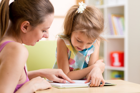 Mother teaching her child daughter to read