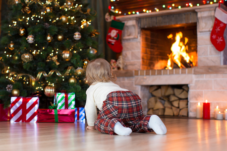 Child toddler crawling to gifts lying under Christmas treeの写真素材