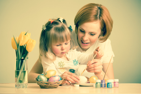 mother and child daughter with brush coloring easter eggsの写真素材