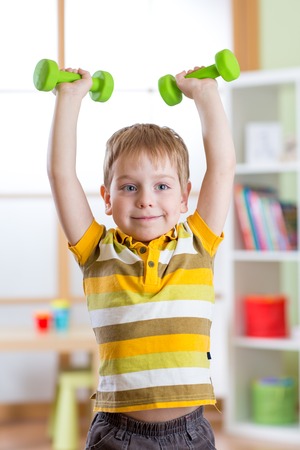 Smiling kid little boy exercising with dumbbells. Healthy life and sport concept.の写真素材