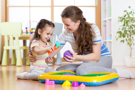 Child girl and mother playing with kinetic sand at homeの写真素材