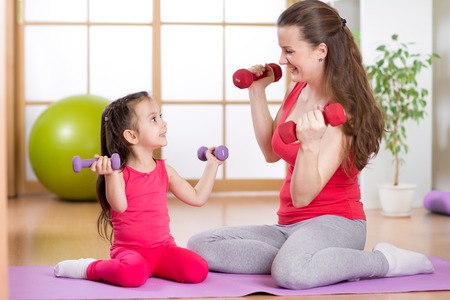 Woman and child daughter doing fitness exercises  with dumbbellsの写真素材