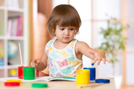 cute child girl painting her fingers in bright colorsの写真素材