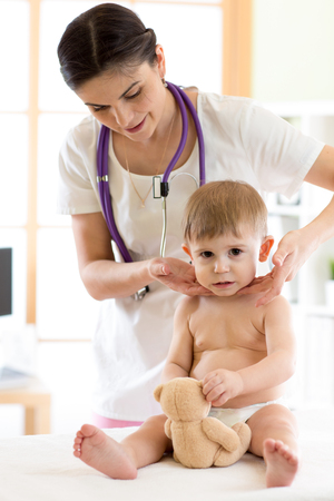 Doctor touching the throat of child patient in the officeの写真素材