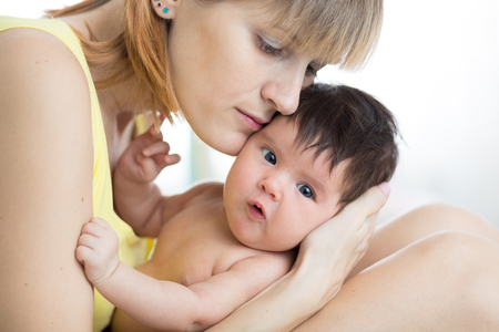 Happy mother with newborn baby at home. Family, child and parenthood concept.の写真素材