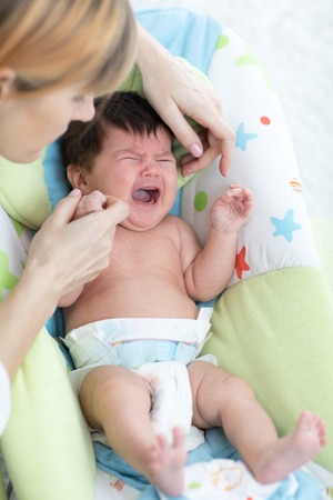 Mother calms newborn baby. Child is crying and screaming during colicの写真素材
