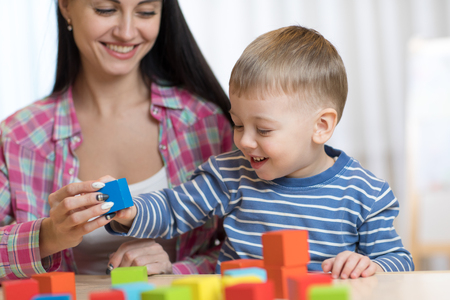 Pretty woman and her son little child playing with building blocksの写真素材
