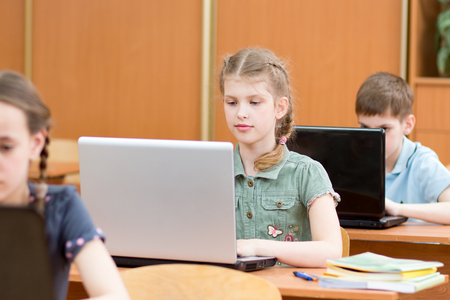 school children using laptop at lesson in classroomの写真素材
