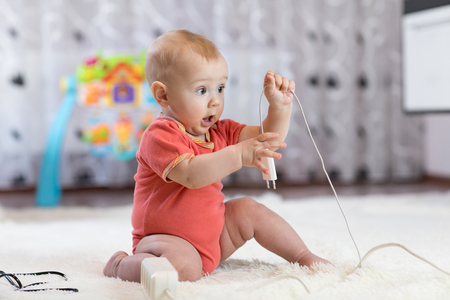 Funny baby boy pulling cables from electrical extensionの写真素材